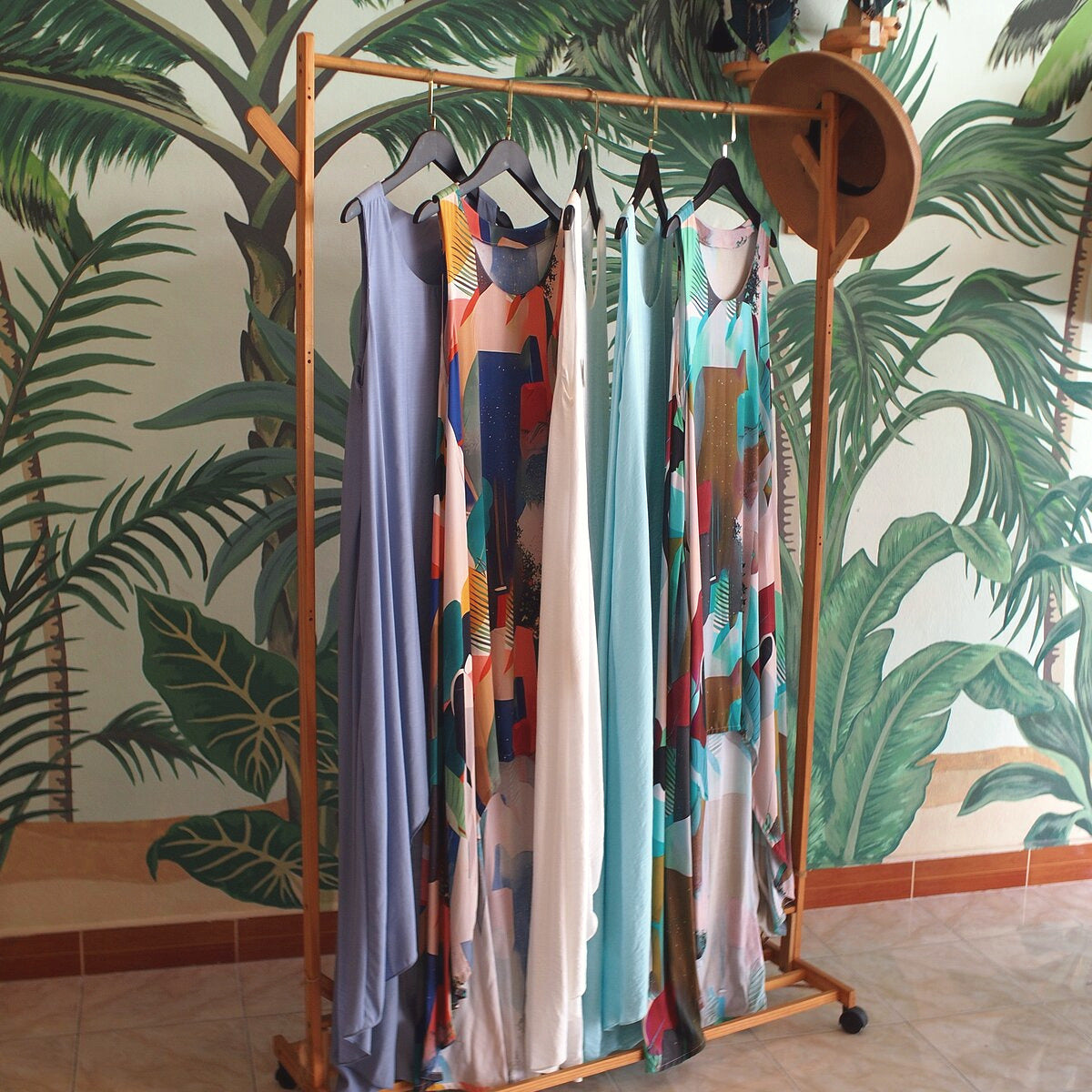 Dresses on a wooden rack in front of the painted palm mural inside the Best Plan No Plan shop on Koh Phangan